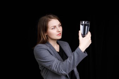 Bir bardak suya bakan bir kadının portresi. Siyah arkaplanda bir portre