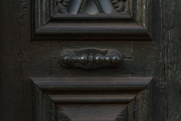 Wooden dark aged textured entrance with rings door handles and metal details. Architecture background. Old wooden door with rivets and aged metal door handle in the form of ring