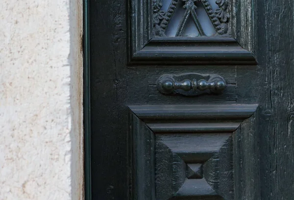 Wooden dark aged textured entrance with rings door handles and metal details. Architecture background. Old wooden door with rivets and aged metal door handle