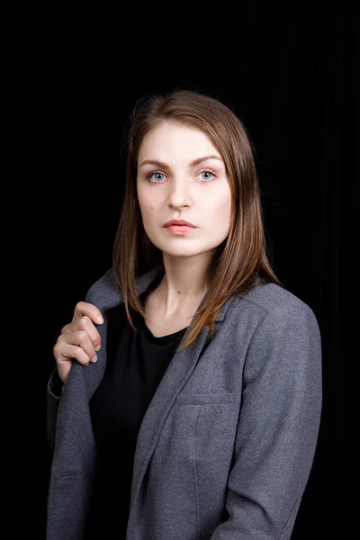 Retrato de una joven mujer de negocios con chaqueta gris sobre fondo negro — Foto de Stock