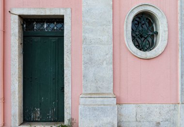 Eski pembe duvarlı ev cephesi yeşil kapalı kapılı ve yuvarlak pencereli duvar dokusu arka planında