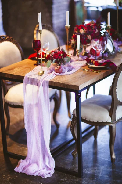Flores buquê de rosa, rosas vermelhas e brancas no vaso, prato com romãs, belas velas e cartões de convite na mesa de casamento coberta com toalha de mesa rosa — Fotografia de Stock