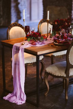 Vazodaki pembe, kırmızı ve beyaz güller, narlı tabaklar, güzel mumlar ve pembe masa örtüsüyle kaplı davetiye kartları.