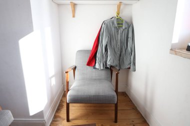 Güneşli odada erkek gömleklerini rahat bir sandalyenin altına as.