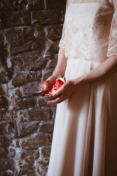 웨딩 드레스를 입은 여자는 야자나무에 석류를 들고 있다 — 스톡 사진