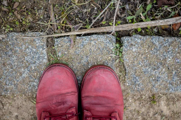 Czerwone buty podróżnika mocno stoją na kamiennym chodniku. — Zdjęcie stockowe