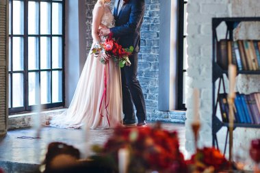 Gelinlik ve damat giymiş gelin pencerenin yanında sarılıyor. Yüzü olmayan fotoğraf