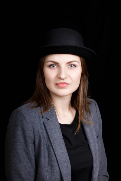 Linda chica joven en sombrero y chaqueta gris sobre fondo negro — Foto de Stock