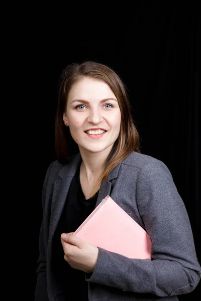 Niedliche junge Frau in einer Business-Jacke mit einem rosa Notizbuch in der Hand — Stockfoto