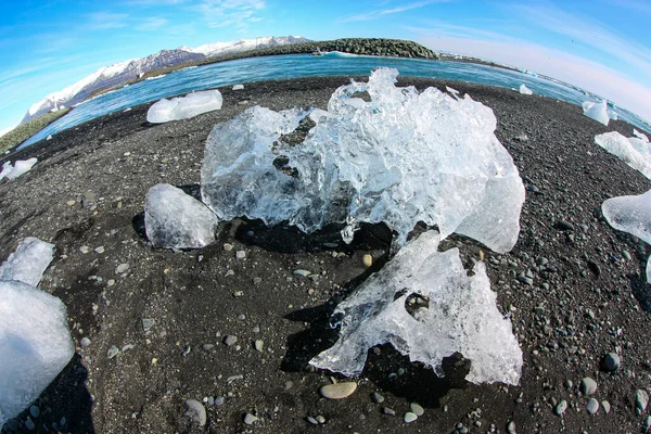 氷の塊はアイスランドの「ダイヤモンドビーチ」の黒い火山砂の上に横たわっています — ストック写真