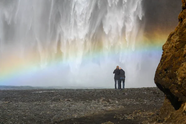 Potente cascata in Islanda con un arcobaleno e le persone di fronte ad esso — Foto Stock