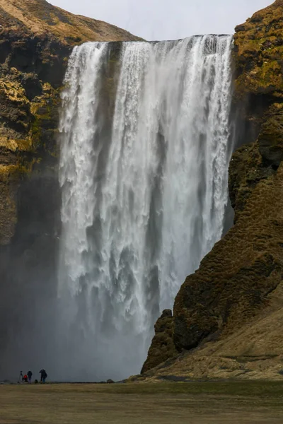 Potente cascata in Islanda con un arcobaleno e le persone di fronte ad esso — Foto Stock