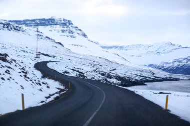 İzlanda 'da kış manzarasında yol. Yan tarafı karla kaplı asfalt yol.