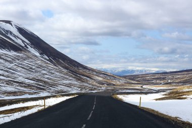 İzlanda 'da kış manzarasında yol. Yan tarafı karla kaplı asfalt yol.