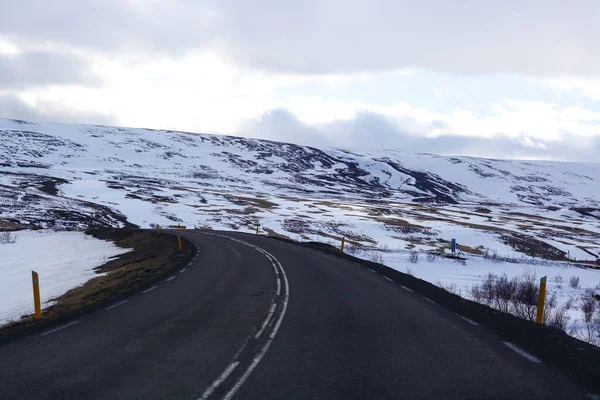 İzlanda 'da kış manzarasında yol. Yan tarafı karla kaplı asfalt yol. — Stok fotoğraf