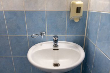 Otel odasındaki banyonun duvarında lavabo ve sıvı el sabunu var.
