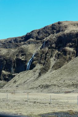İzlanda 'da küçük bir şelale. Yerdeki volkanik kayalar