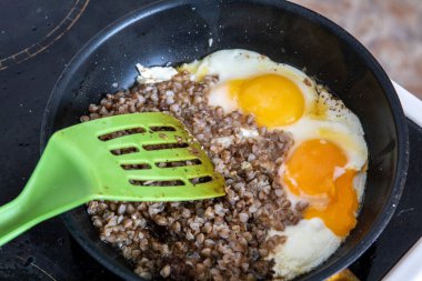 Şef kahvaltıyı hazırlar. Haşlanmış karabuğday ve tavada iki yumurta.