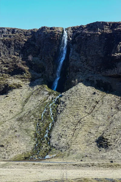 Una pequeña cascada en Islandia. Las rocas volcánicas que yacen en el suelo — Foto de Stock