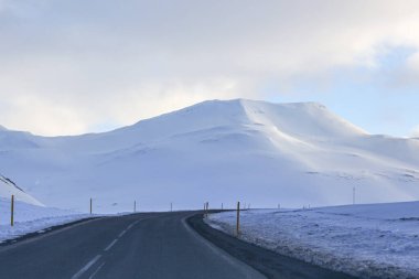 Karlı dağların ve gökyüzünün arka planındaki karanlık yol