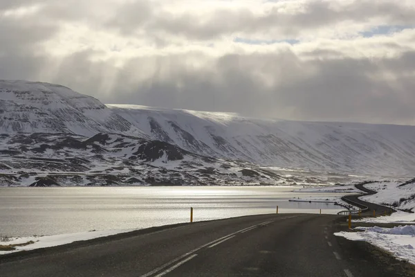 Route asphaltée sombre sur le fond des montagnes et de l'océan. La tournée en Islande. La chaleur géothermique de cette façon — Photo