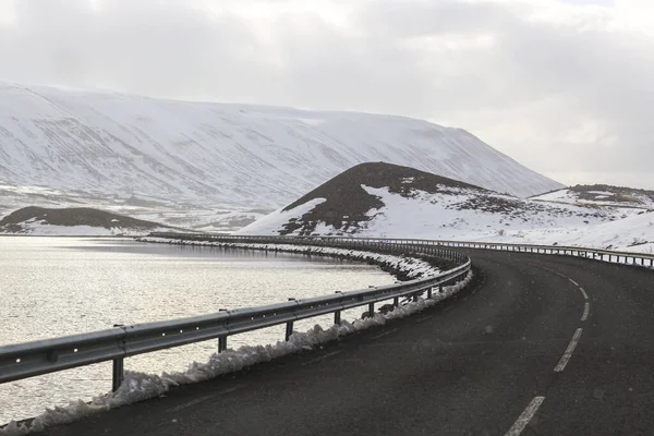 Ciemna droga na tle śnieżnych gór i nieba — Zdjęcie stockowe