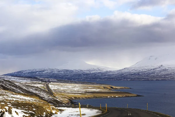 Donkere weg op de achtergrond van besneeuwde bergen en lucht — Stockfoto