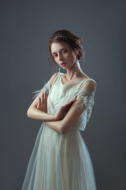 Omuzlarında parlak elementler olan şeffaf bir elbiseyle geçmişe dönük bir kızın eski moda portresi..