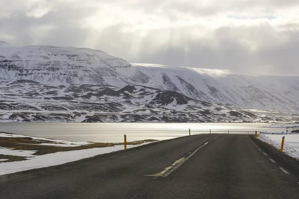 Camino de asfalto oscuro en el fondo de las montañas y el océano. La gira por Islandia. El calor geotérmico de esta manera — Foto de Stock