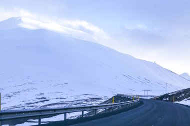 Karlı dağların ve gökyüzünün arka planındaki karanlık yol