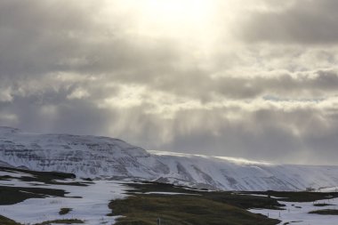 Dağların ve okyanusun arka planında asfalt yol. İzlanda turu. Jeotermal ısı bu tarafa.