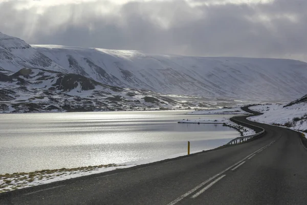 Route asphaltée sombre sur le fond des montagnes et de l'océan. La tournée en Islande. La chaleur géothermique de cette façon — Photo