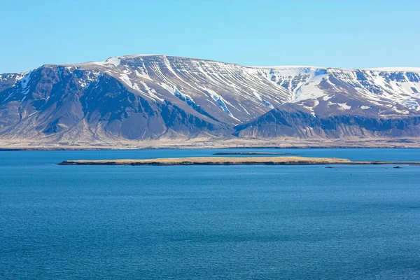 雪に覆われた海の近くの雄大な山々。アイスランドの風景 — ストック写真