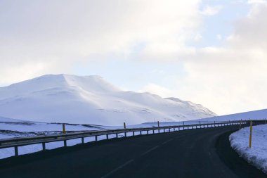 Karlı dağların ve gökyüzünün arka planındaki karanlık yol