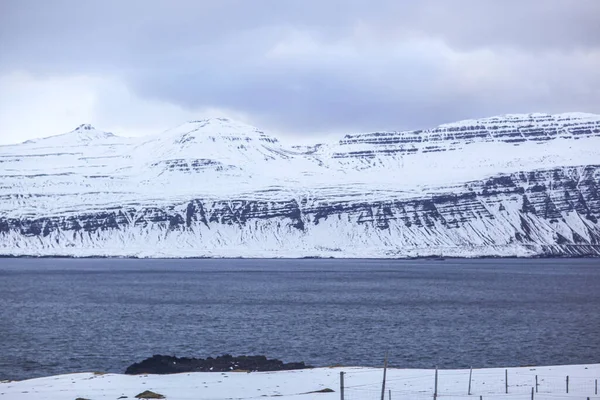 Land och berg täckta med snö, nära havet. — Stockfoto