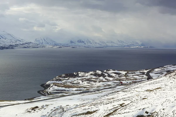 Den svarta vägen nära de snöiga bergen. Isländskt landskap — Stockfoto