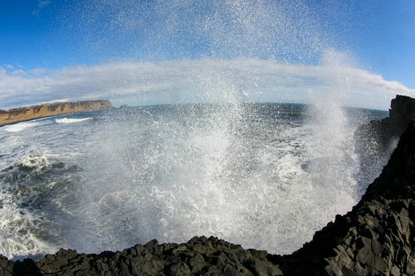 Океанская волна обрушилась на прибрежные базальтовые породы в Исландии. Морской спрей — стоковое фото