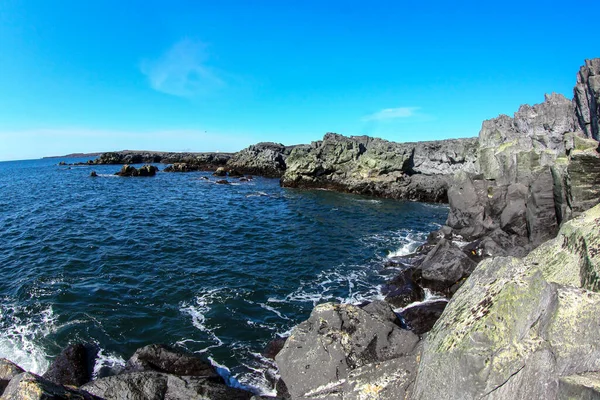 Basalt rotsen aan de kust van de blauwe oceaan in IJsland. — Stockfoto