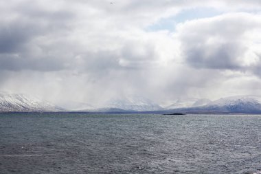 İzlanda 'da okyanusta karla kaplı güzel dağlar. Yağmurlu hava