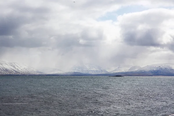 Belas montanhas cobertas de neve no oceano na Islândia. Tempo chuvoso — Fotografia de Stock