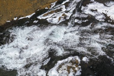 Kayaların ve karın arasında İzlanda 'da hızlı kaynayan bir nehir