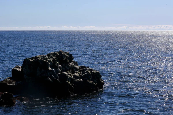 Roccia basaltica nell'oceano. Ondate di luce sull'acqua — Foto Stock