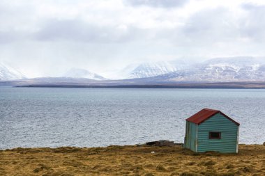Okyanusun arka planında ve karla kaplı dağlarda yalnız bir ev. Mahremiyet ve güç yeri