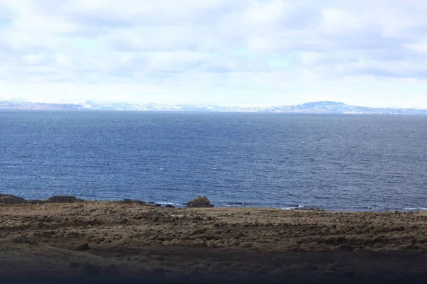 Linia brzegowa oceanu i piękne ośnieżone góry na horyzoncie. Krajobraz Islandii — Zdjęcie stockowe