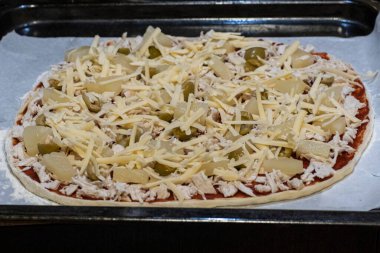 Fırına girmeden önce tavuk, ananas, zeytin ve peynirli çiğ pizza.