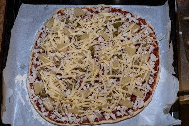 Fırına girmeden önce tavuk, ananas, zeytin ve peynirli çiğ pizza.