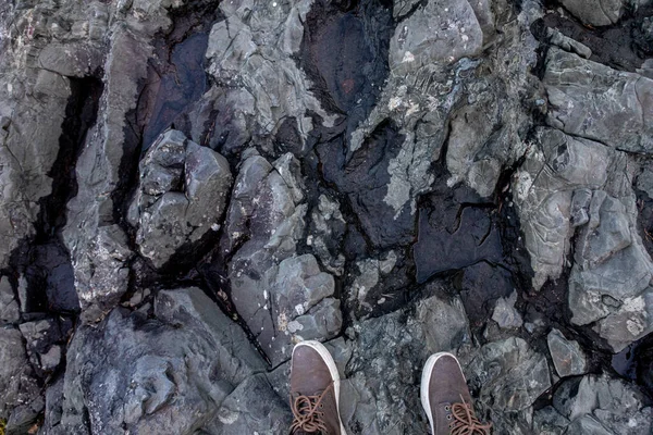 Buty człowieka na dużych skałach lawy. Podróżować po ziemi — Zdjęcie stockowe
