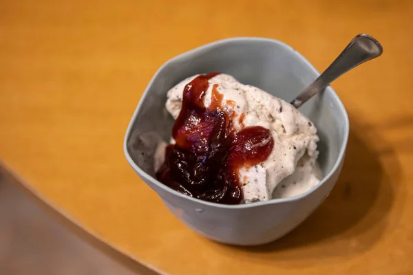 ramekin with soft ice cream, jam and spoon in a glass