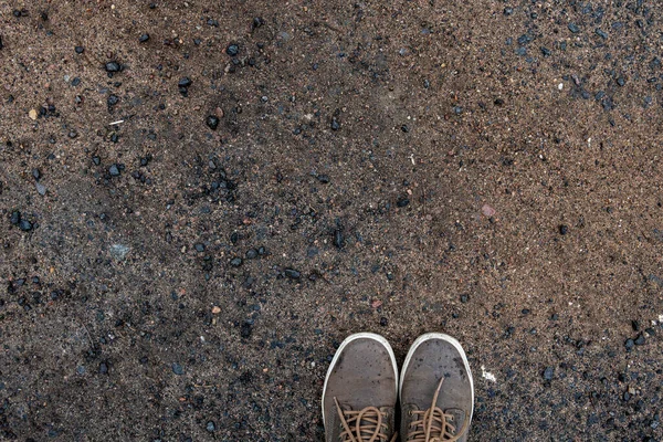 旅行者の靴はでこぼこ道にあります。テキストのテクスチャと背景。人生の道の象徴 — ストック写真