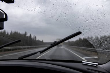 Yağmurlu bir havada hareket halindeki bir arabanın penceresinden manzara. Odaklanamayan pistler ve arabalar. Görüş koşullarında hız